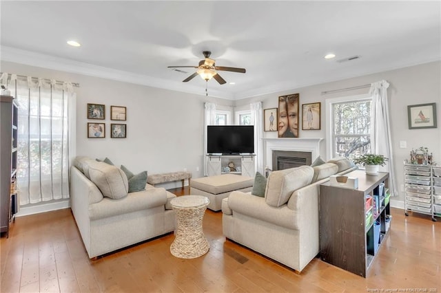 living area with ceiling fan, light wood-style floors, a glass covered fireplace, recessed lighting, and baseboards