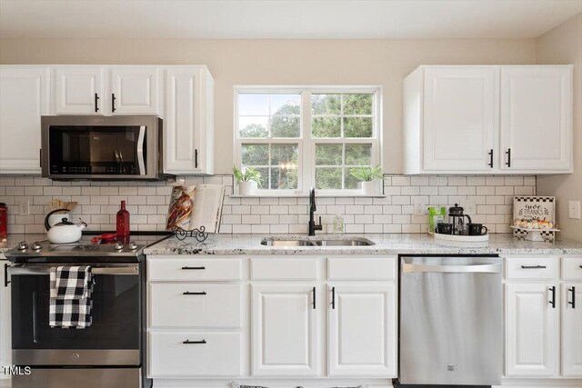 1969 Bowles Ave, Creedmoor, NC 27522 - kitchen featuring appliances with stainless steel finishes, a sink, light stone counters, and white cabinetry