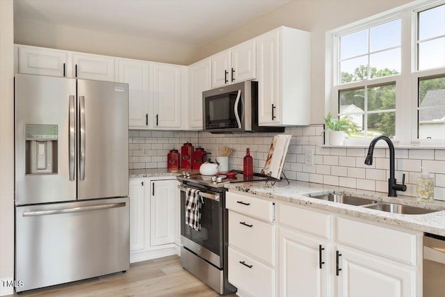 1969 Bowles Ave, Creedmoor, NC 27522 - kitchen with appliances with stainless steel finishes, a sink, white cabinets, light stone counters, and tasteful backsplash
