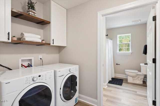1969 Bowles Ave, Creedmoor, NC 27522 - laundry area featuring washer and clothes dryer, baseboards, light wood-style flooring, and cabinet space