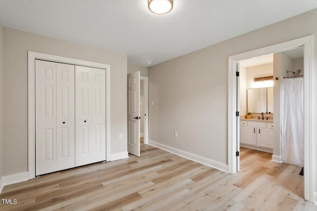 1969 Bowles Ave, Creedmoor, NC 27522 - unfurnished bedroom featuring light wood-style floors, a closet, baseboards, ensuite bath, and a sink