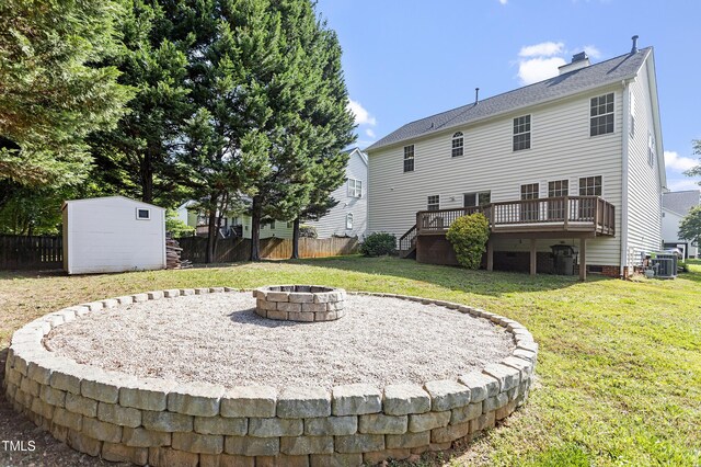 back of property with an outdoor fire pit, a wooden deck, a shed, a chimney, and an outbuilding