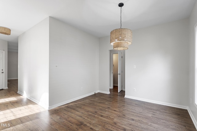 unfurnished dining area featuring wood finished floors, a chandelier, and baseboards