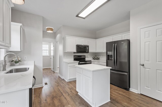 kitchen featuring refrigerator with ice dispenser, black microwave, stainless steel electric range oven, a sink, and white cabinets