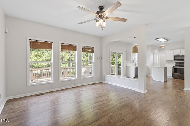 unfurnished living room featuring wood finished floors, ceiling fan, and baseboards