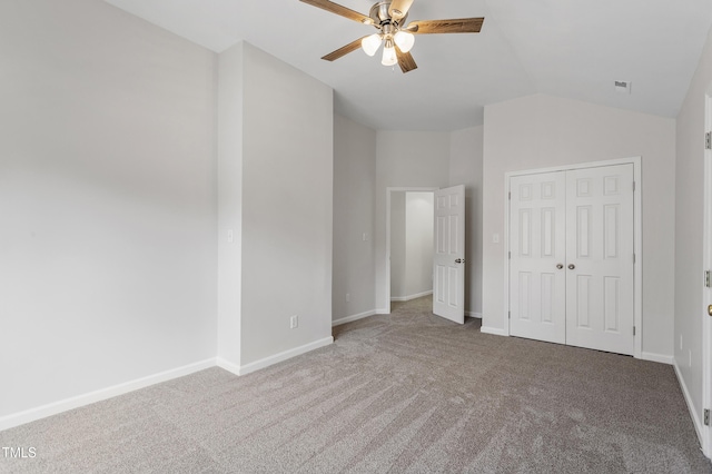 unfurnished bedroom featuring carpet floors, vaulted ceiling, a closet, baseboards, and a ceiling fan