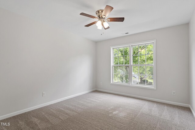 carpeted spare room with baseboards and a ceiling fan