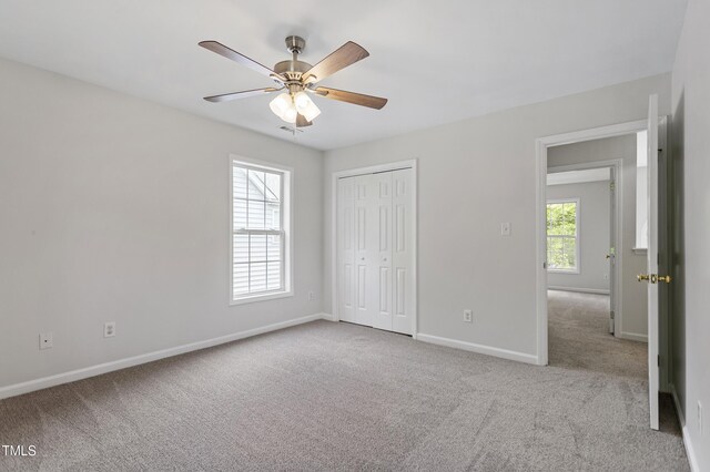 unfurnished bedroom featuring carpet floors, baseboards, a closet, and ceiling fan