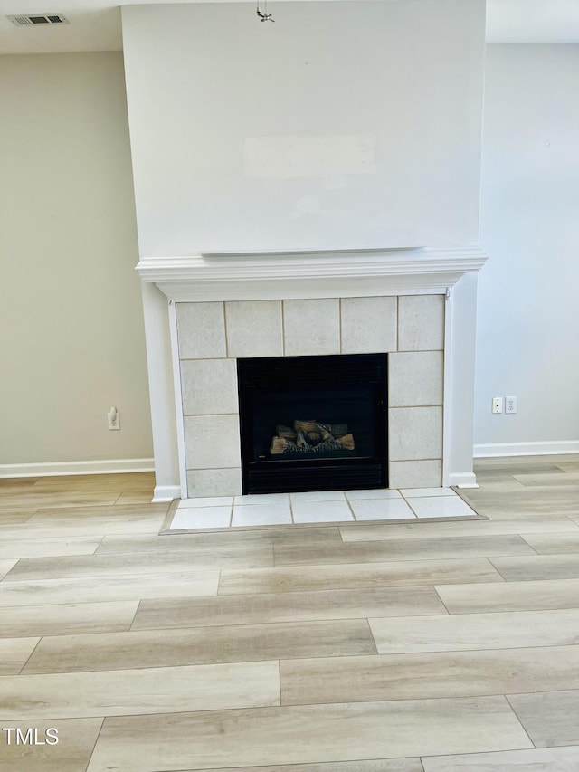 detailed view of a fireplace, wood finished floors, and baseboards