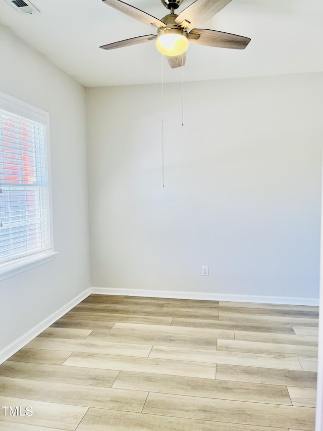 empty room featuring a ceiling fan, light wood finished floors, and baseboards