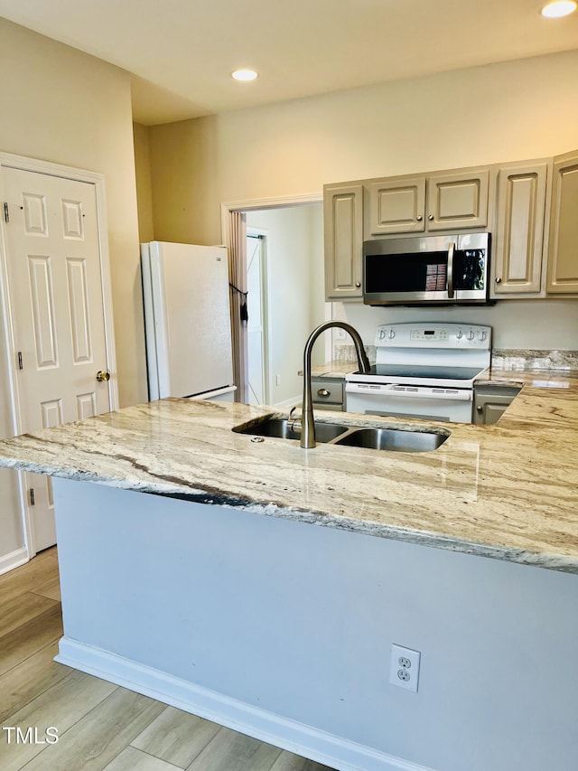 kitchen with white appliances, a sink, light stone countertops, recessed lighting, and light wood finished floors