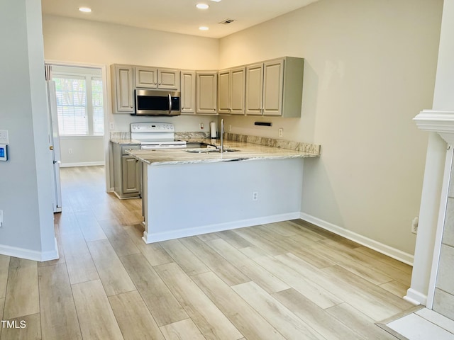 kitchen featuring white appliances, a peninsula, baseboards, recessed lighting, and light wood-style floors