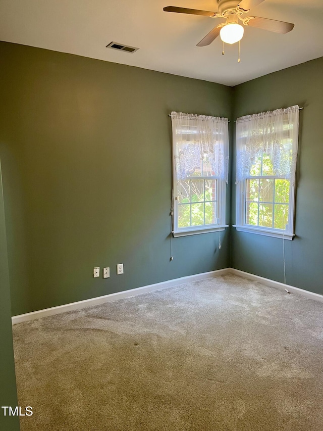 carpeted spare room featuring a ceiling fan and baseboards