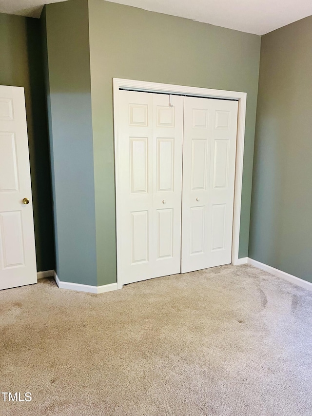 unfurnished bedroom with carpet flooring, baseboards, and a closet
