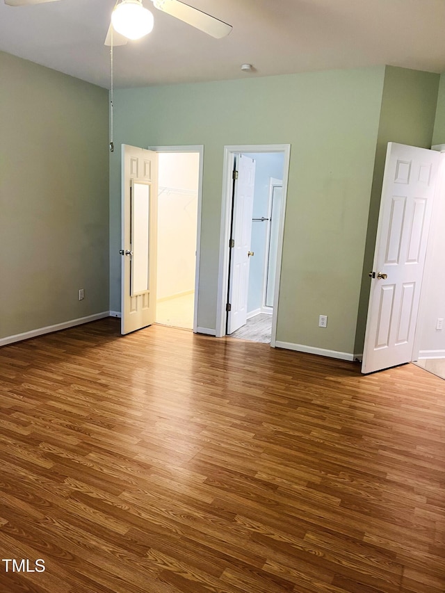 unfurnished room featuring wood finished floors, ceiling fan, and baseboards