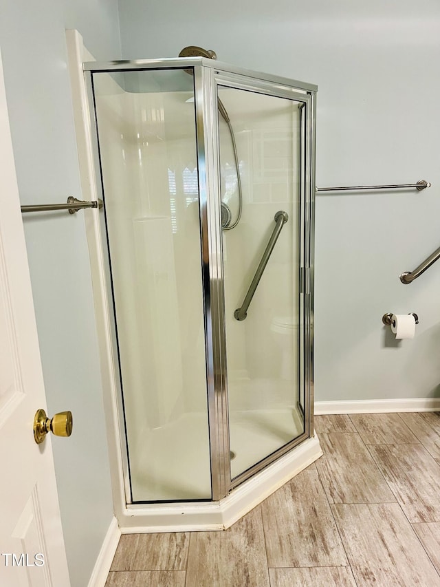 bathroom with a shower stall, wood finished floors, and baseboards