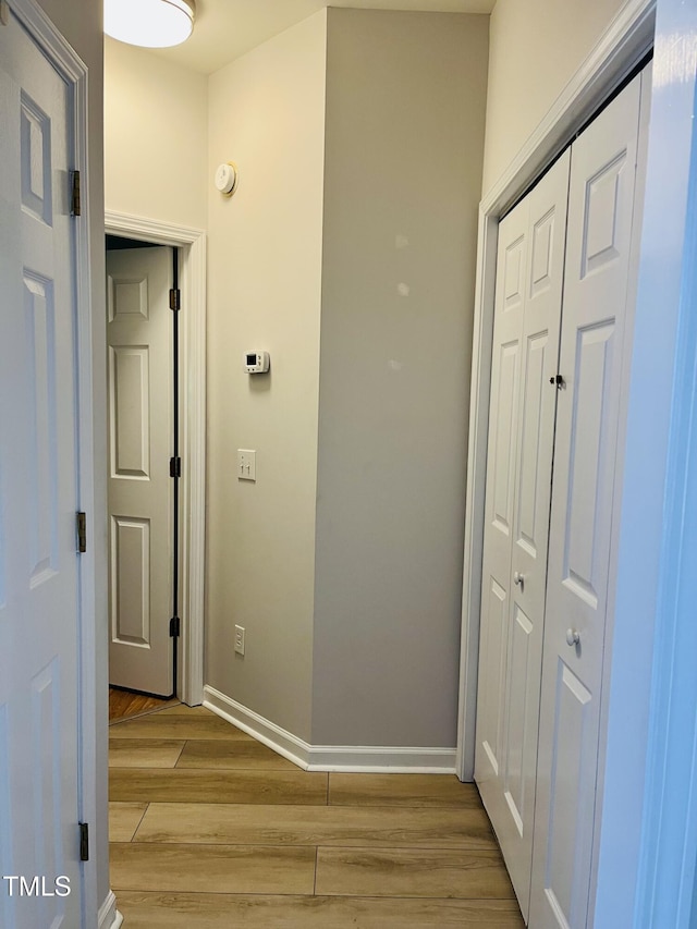 hall with light wood-type flooring and baseboards