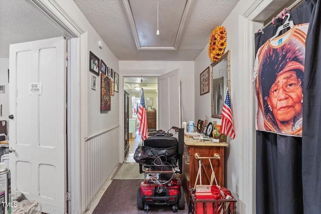 corridor with a textured ceiling, carpet floors, and attic access