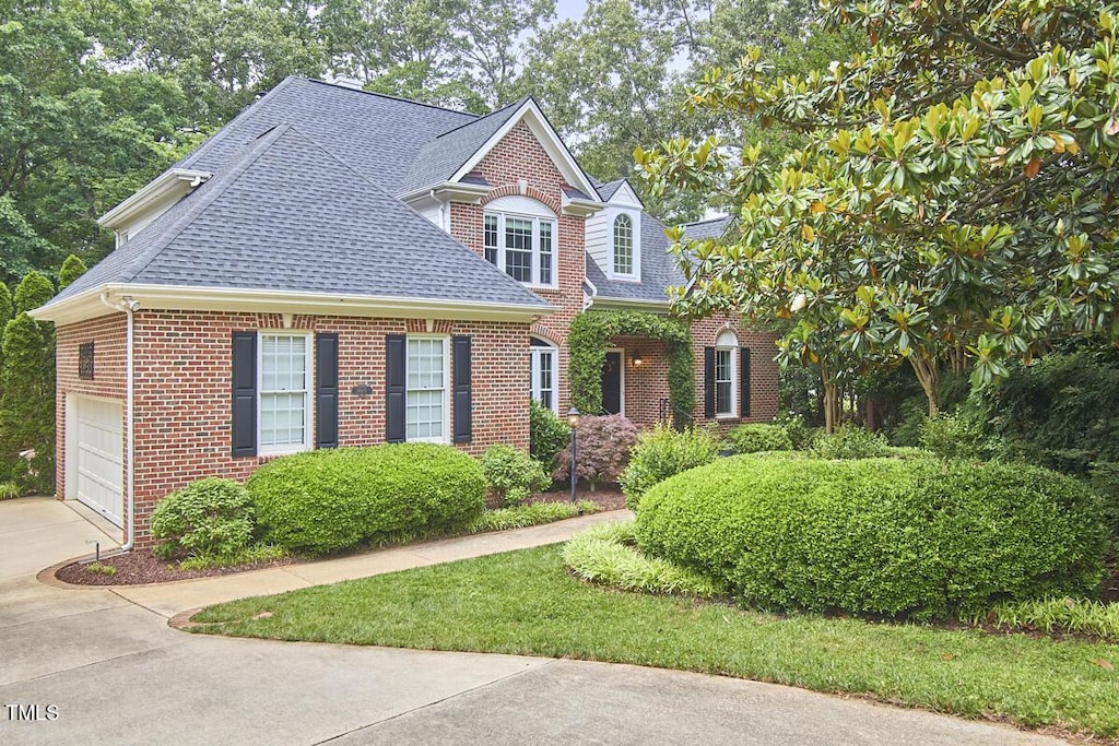 view of front of home featuring brick siding, a shingled roof, concrete driveway, and a garage