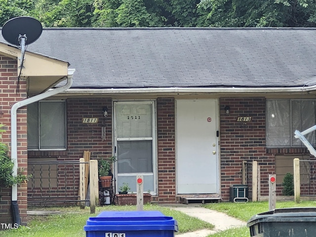 view of front of home featuring brick siding, covered porch, and a shingled roof