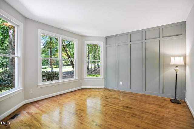 unfurnished bedroom featuring multiple windows, wood finished floors, and baseboards