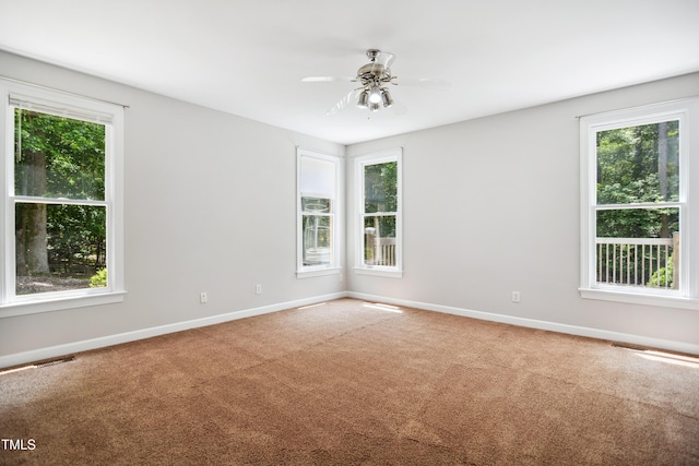 carpeted empty room with healthy amount of natural light, baseboards, and a ceiling fan