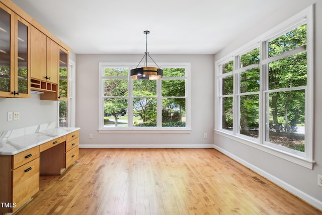 kitchen featuring baseboards, a chandelier, light wood finished floors, and healthy amount of natural light