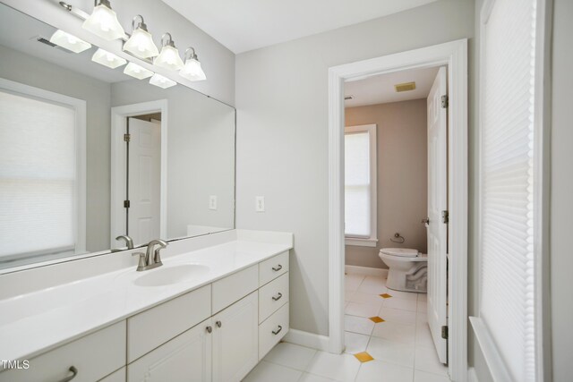 bathroom with toilet, tile patterned floors, vanity, and baseboards