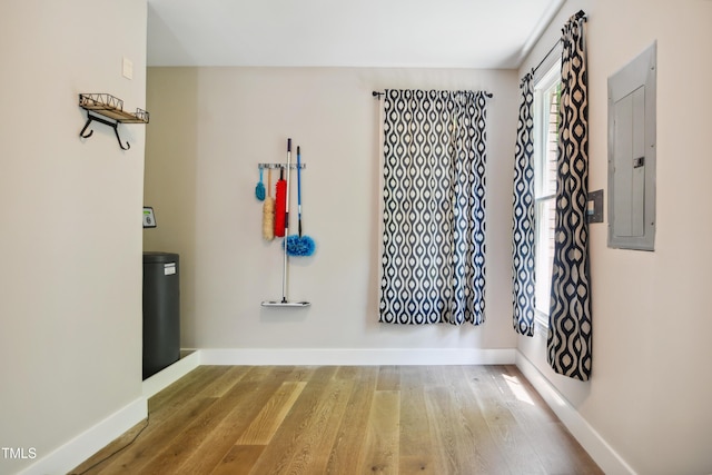 unfurnished room with electric panel, wood finished floors, and baseboards