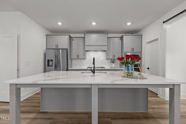 825 Abbyberry Dr, Wake Forest, NC 27587 - kitchen with appliances with stainless steel finishes, gray cabinets, a large island, backsplash, and light stone counters