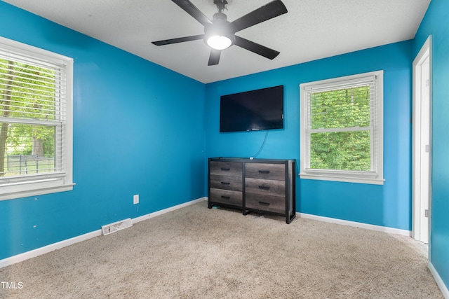 901 Currin Perry Rd, Zebulon, NC 27597 - unfurnished bedroom featuring carpet, multiple windows, baseboards, ceiling fan, and a textured ceiling