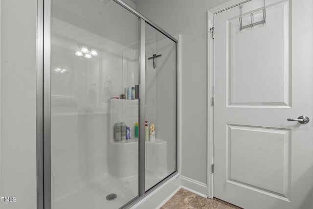 bathroom featuring a shower stall and baseboards