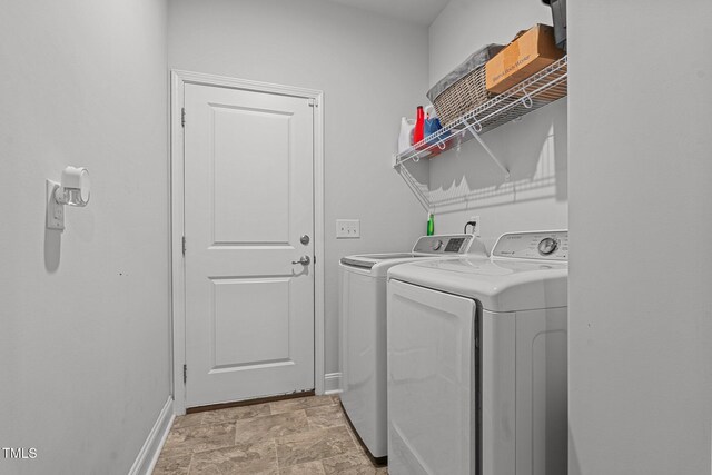 washroom with washing machine and clothes dryer, baseboards, and stone finish floors