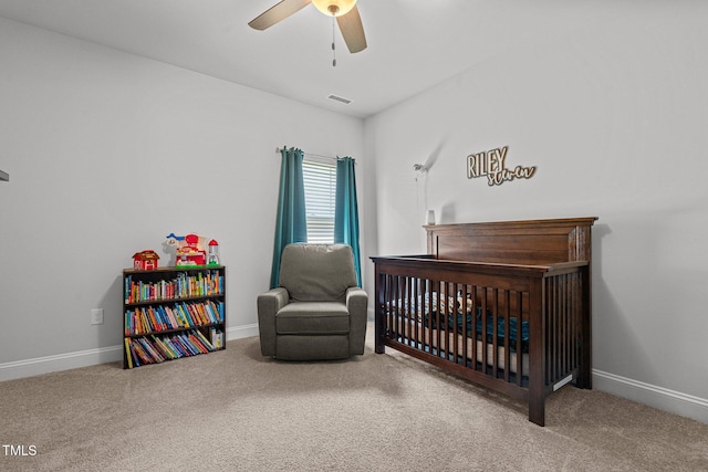 bedroom featuring carpet flooring, a crib, baseboards, and ceiling fan