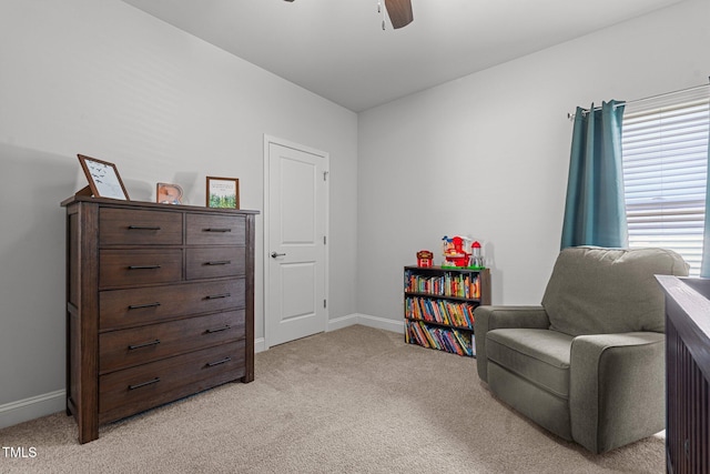 living area featuring light carpet, baseboards, and ceiling fan