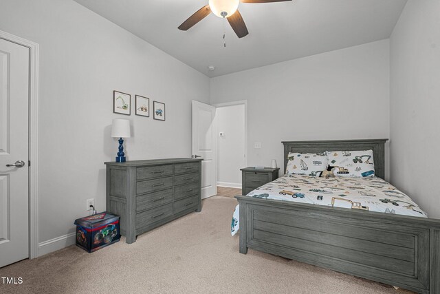 bedroom featuring light carpet, a ceiling fan, and baseboards