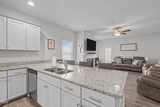 kitchen with open floor plan, a peninsula, stainless steel dishwasher, a sink, and a ceiling fan