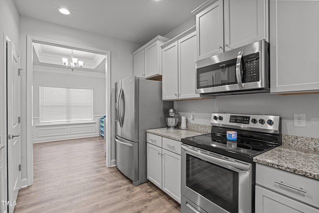 kitchen featuring appliances with stainless steel finishes, a raised ceiling, crown molding, a chandelier, and recessed lighting