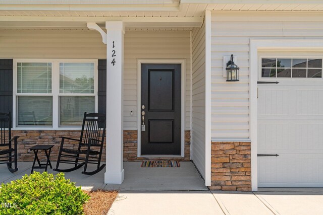 entrance to property with a porch and stone siding