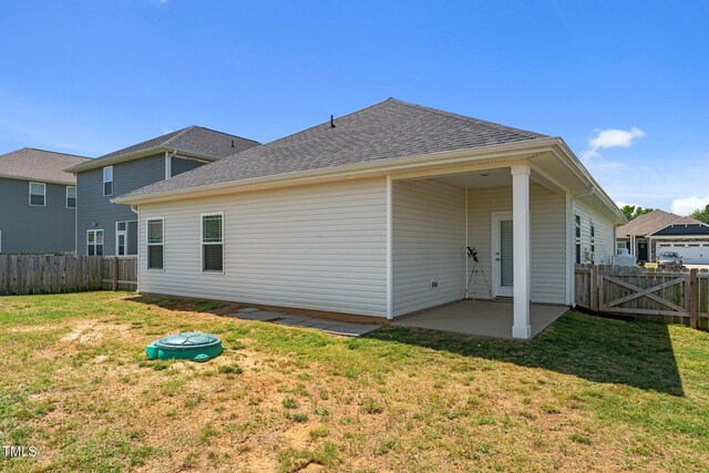 rear view of property featuring a patio, roof with shingles, and a gate