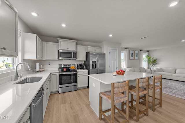 kitchen with stainless steel appliances, a sink, healthy amount of natural light, light wood-type flooring, and recessed lighting