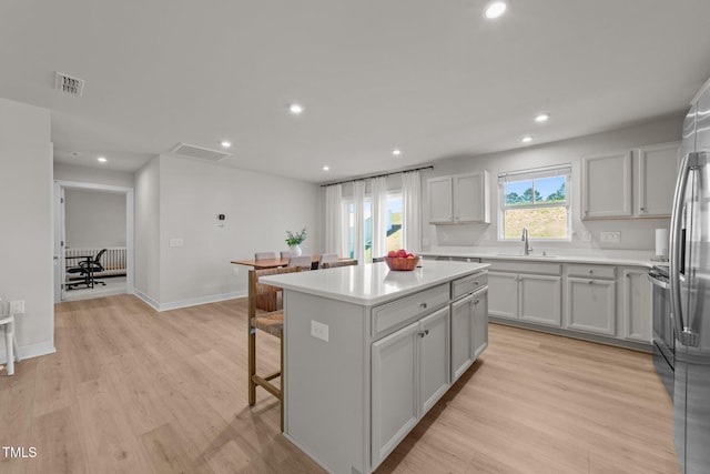 kitchen with a kitchen island, light wood-type flooring, a breakfast bar, recessed lighting, and light countertops
