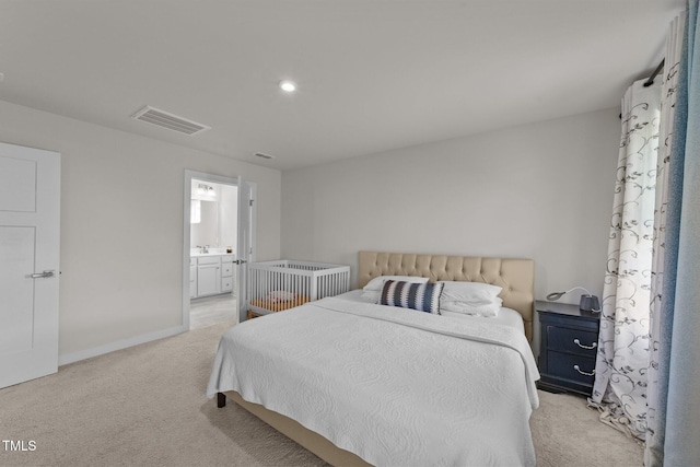 bedroom featuring light colored carpet, connected bathroom, baseboards, and a sink