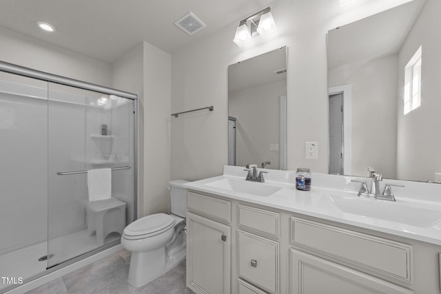 bathroom with a shower stall, toilet, double vanity, and tile patterned floors