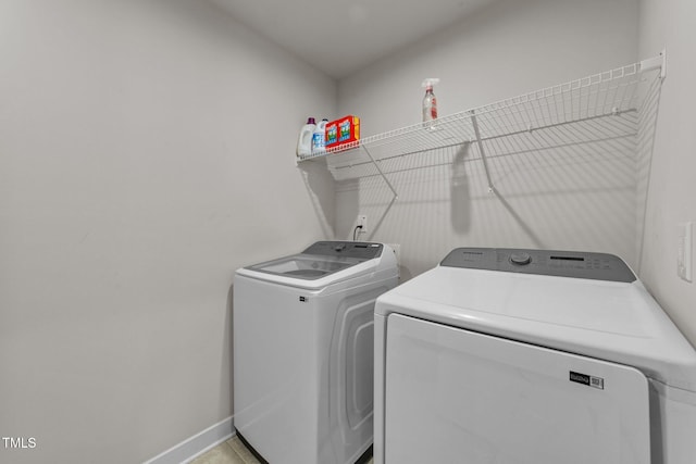 laundry area with washing machine and clothes dryer and baseboards