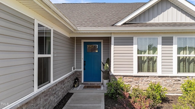 property entrance featuring a shingled roof, stone siding, and board and batten siding