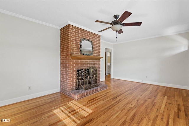 unfurnished living room with baseboards, crown molding, a brick fireplace, wood finished floors, and ceiling fan