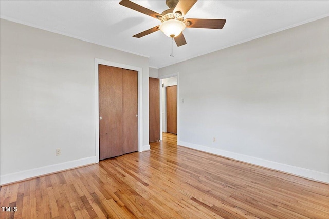 unfurnished bedroom with baseboards, light wood-style floors, ornamental molding, a ceiling fan, and a closet