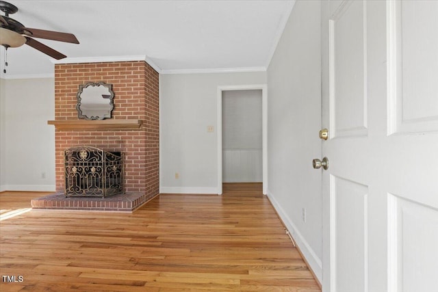 unfurnished living room featuring crown molding, ceiling fan, light wood finished floors, a brick fireplace, and baseboards