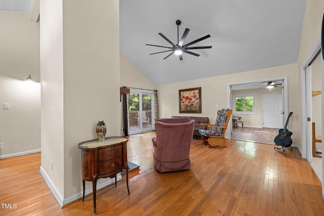 living area with ceiling fan, high vaulted ceiling, hardwood / wood-style flooring, and healthy amount of natural light